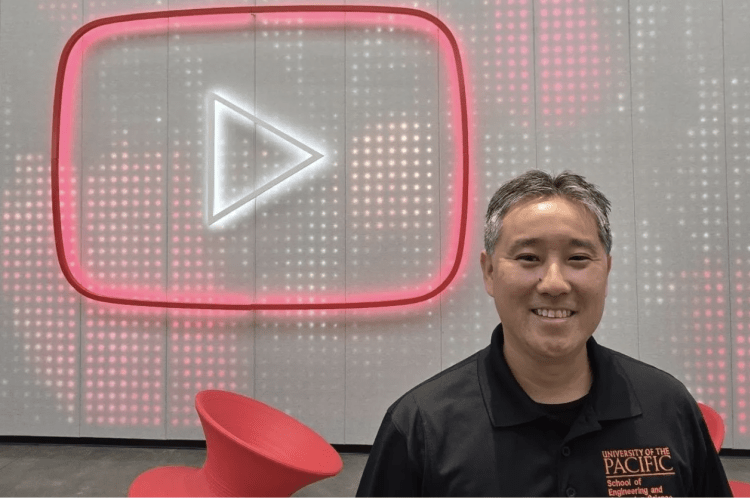 A man wearing a black polo shirt sits in front of the YouTube logo